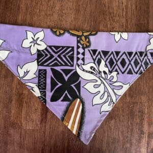 A purple, floral and geometric patterned cloth on a wooden surface.