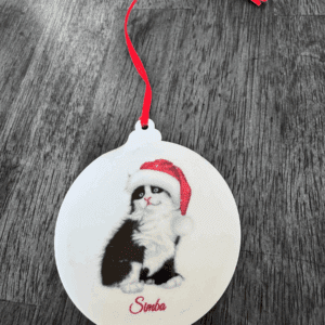 A cat wearing a Santa hat on a Christmas ornament with the name 'Soda'.